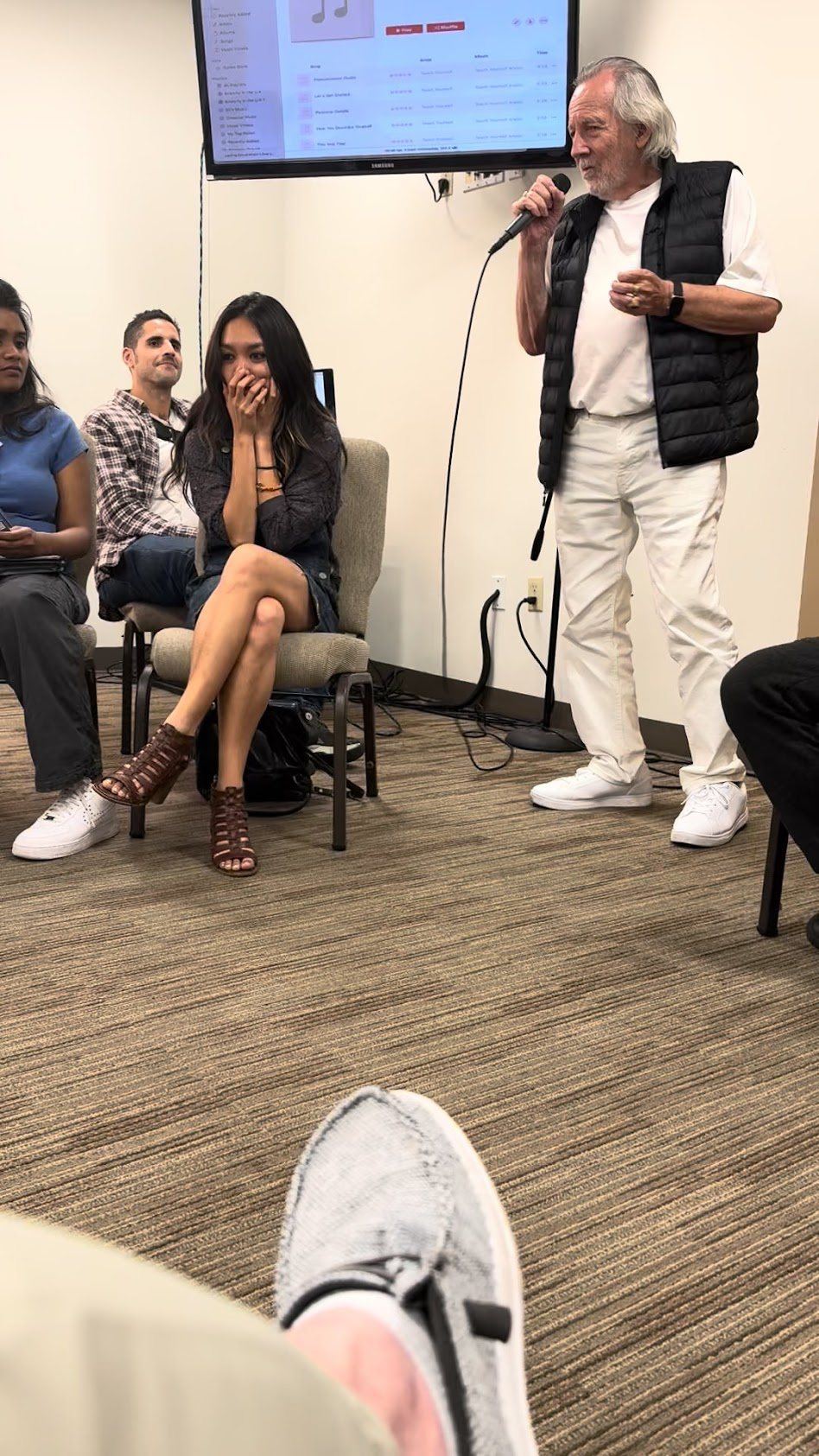 Joseph speaking to a seated room, microphone in hand